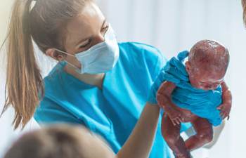 Hebamme hält neugeborenes Baby nach der Entbindung.